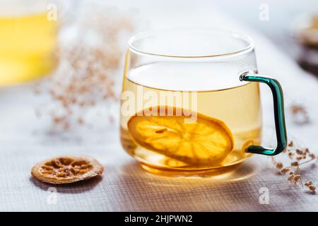 Tasse de thé camomille dans une tasse transparente servie avec une tranche de citron et d'orange.Pause thé. Banque D'Images