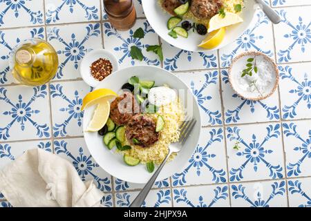 Patties de dinde aux herbes servies avec du couscous et de la salade fraîche Banque D'Images