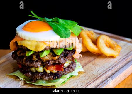 Cheeseburger au saumon frais et rôti de bœuf accompagné de frites et d'œufs sur une table en bois Banque D'Images