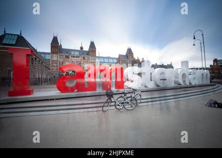 Des lettres énormes dans le signe 'I Amsterdam' avec un vélo garée en face du Rijksmuseum Amsterdam Holland exposition longue Banque D'Images