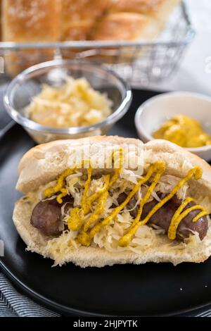 Brattes de bière avec choucroute sur un gros pain arrosé de moutarde. Banque D'Images