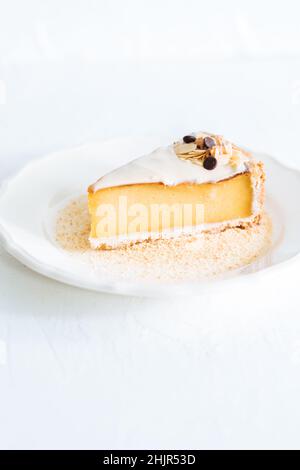 Flan français sur plaque blanche avec chapelure de biscuit autour, avec amandes sur le dessus.Gâteau sur fond blanc lumineux, dessert français traditionnel Banque D'Images