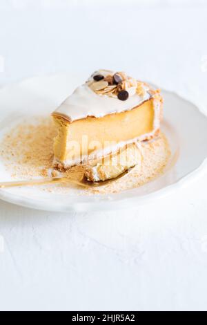 Flan français sur plaque blanche avec chapelure de biscuit autour, avec amandes sur le dessus.Gâteau sur fond blanc lumineux, dessert français traditionnel Banque D'Images