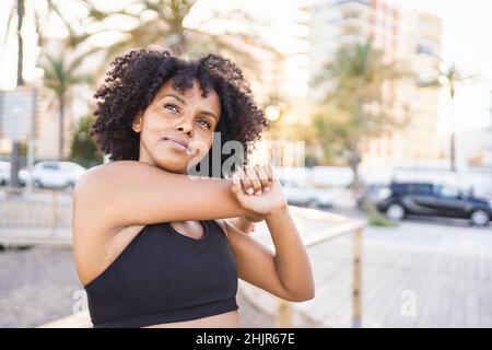 femme noire souriant avec des cheveux afro s'étendant sur la plage Banque D'Images