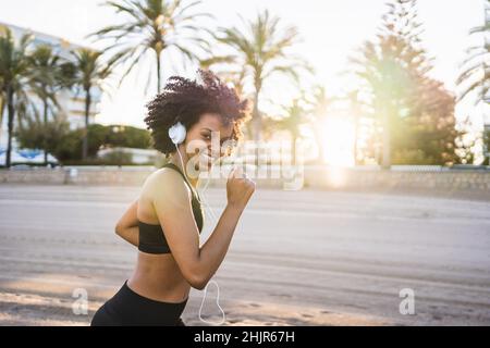 une femme noire aux cheveux afro se met à sourire sur la plage Banque D'Images