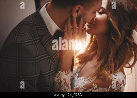 Mariée et marié élégants, se serpente doucement dans la rue européenne. Magnifique couple de jeunes mariés qui s'embrasse près d'un bâtiment ancien. Moment romantique. Banque D'Images