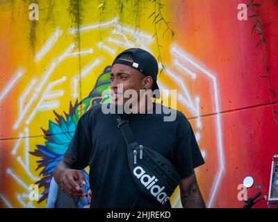 Medellin, Antioquia, Colombie - novembre 11 2021 : le jeune homme latin avec T-shirt noir chante Hip-Hop sans microphone contre le mur coloré Banque D'Images