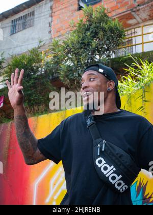 Medellin, Antioquia, Colombie - novembre 11 2021 : le jeune homme latin avec T-shirt noir chante Hip-Hop sans microphone contre le mur coloré Banque D'Images