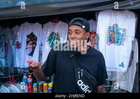 Medellin, Antioquia, Colombie - novembre 11 2021 : le jeune homme latin avec T-shirt noir et casquette vend des vêtements et des bières Banque D'Images
