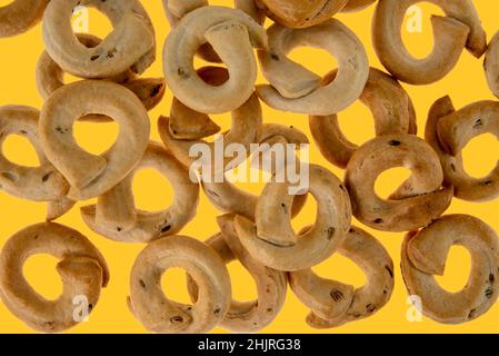 Taralli tarallini ou tarallucci avec graines de fenouil de Puglia, Italie, isolé sur fond jaune dans la vue de dessus Banque D'Images