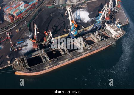 Vladivostok, Russie - 27 janvier 2022 : Vue de dessus du terminal de charbon du port maritime.Le transporteur de vrac est chargé de charbon. Banque D'Images