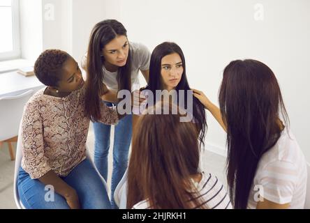 Groupe de femmes assis à côté d'une jeune femme triste et bouleversée ensemble de soutenir et de la réconforter. Banque D'Images