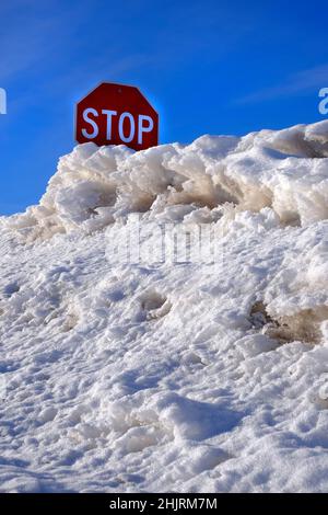 Panneau d'arrêt rouge enseveli dans la neige profonde dérive en hiver Banque D'Images