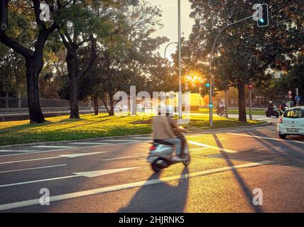 Scooter en passant par la rue O’Donell à côté du parc Retiro au coucher du soleil.Madrid.Espagne. Banque D'Images