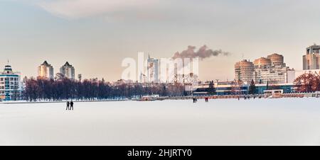 Paysage urbain d'hiver d'Ekaterinbourg, Russie. Glace de l'étang de la ville couverte de neige, bâtiments, personnes. Banque D'Images