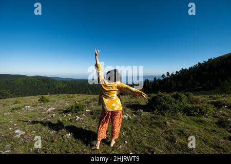 Bonne jeune femme aux armes en relief dansant dans la nature Banque D'Images