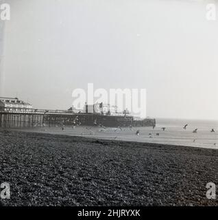 1960s, historique, West Pier, Brighton, West Sussex,Angleterre, Royaume-Uni.Conçu par l'architecte du bord de mer, Eugenius Birch, West Pier a ouvert ses portes en 1866, mais au fil des ans le nombre de visiteurs a diminué et l'embarcadère a fermé en 1975 pour des raisons de sécurité, car des réparations urgentes étaient nécessaires sur sa structure.En raison des coûts élevés impliqués, ils n'ont pas été entrepris et depuis, une combinaison de dommages de tempête et de nombreux incendies signifie que le chef-d'œuvre victorien d'un quai de bord de mer n'est malheureusement plus. Banque D'Images