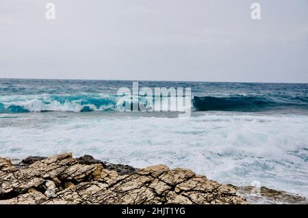 Une grande vague chevauche la côte de l'île croate de Losinj. Une vague qui s'écrase sur la côte rocheuse. Banque D'Images