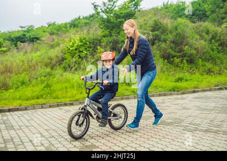 Maman fils apprend à faire du vélo dans le parc Banque D'Images