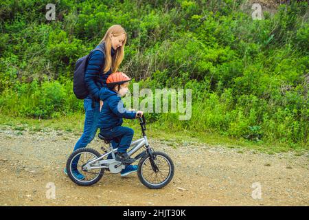 Maman fils apprend à faire du vélo dans le parc Banque D'Images