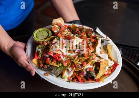 Serveur tenant un plateau de nachos et guacamole Banque D'Images