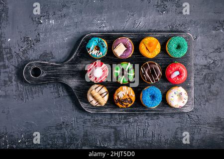 Groupe de mini beignets colorés placés sur fond de bois foncé.Photo vue de dessus.Dessert de finger food Banque D'Images