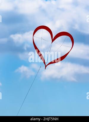 Cerf-volant rouge en forme de coeur dans le ciel bleu avec des nuages au festival de cerfs-volants symbolise l'amour le bonheur dans le mariage d'une vie heureuse Banque D'Images