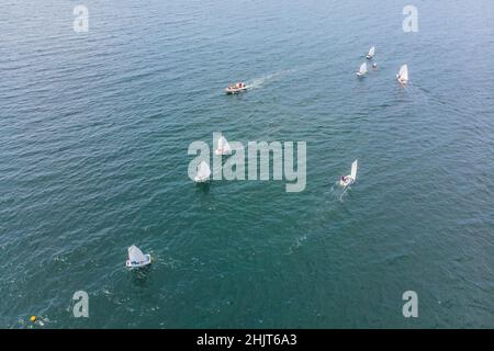 Drone aérien photo de jeunes adolescents sur de petits bateaux à voile en compétition dans la course à la mer émeraude de la Méditerranée Banque D'Images