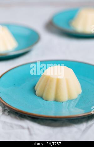Pudding à la vanille sur une assiette en porcelaine bleue avec chapelure au chocolat sur le dessus.Arrière-plan lumineux Banque D'Images
