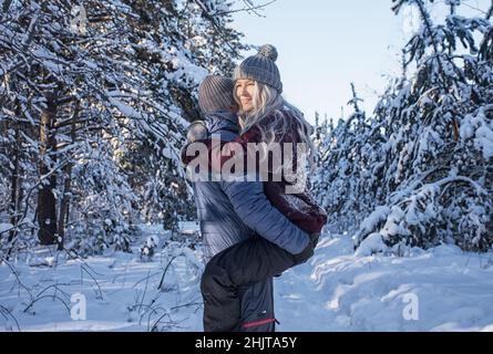 un couple heureux qui se promède dans la forêt enneigée Banque D'Images