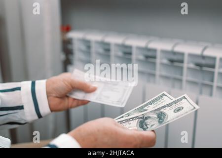 Paiement des factures.Des billets de dollars dans les mains des femmes près de la batterie de radiateur de chauffage à la maison.Frais de chauffage coûteux. Banque D'Images