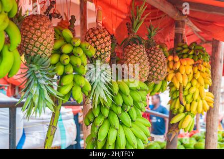 Les bananes et les ananas sont suspendus sous le toit de la rue à Zanzibar, en Tanzanie. Banque D'Images