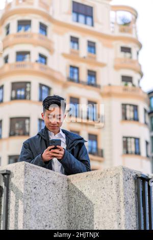 homme asiatique envoyant un message depuis son smartphone Banque D'Images