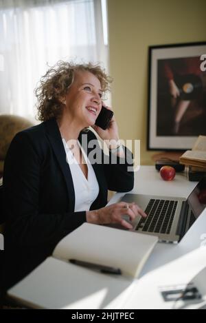 Bonne femme d'affaires parlant sur son téléphone mobile à la maison. Banque D'Images