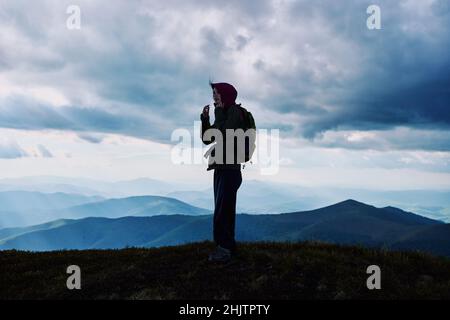 Jeune femme randonnée en montagne au sommet d'une montagne contre un ciel nuageux. Banque D'Images