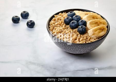 Flocons d'avoine entière avec graines de lin et bleuets et tranches de banane Banque D'Images