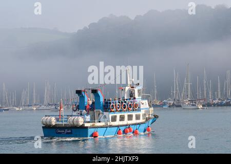 Les gens à bord d'un ferry pour passagers sur la rivière Dart, un matin calme et brumeux, le soleil commence à se briser dans la brume.Dartmouth, Devon, Angleterre, Royaume-Uni Banque D'Images