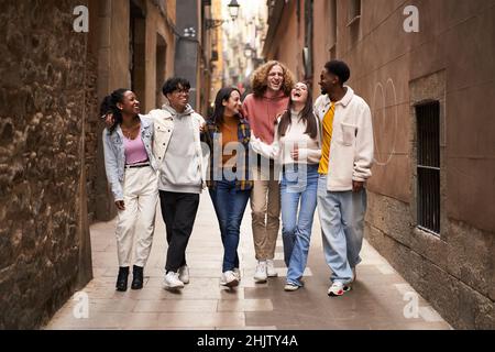 Groupe de jeunes amis heureux marchant dans la rue de la ville.Souriant, les étudiants rient et se amusent Banque D'Images