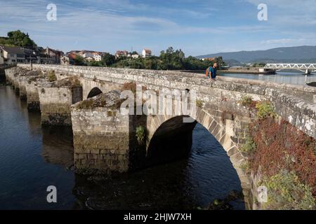 Un pèlerin marchant les Portugais Camino traverse le Ponte médiéval de Pontesampaio à Arcade, Espagne.Cette route du pèlerinage de Camino de Santiago r Banque D'Images