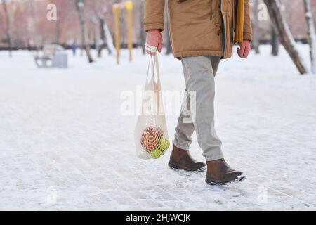 Gros plan d'un homme âgé tenant un sac avec une épicerie qui se trouve dans la rue en hiver après avoir fait du shopping Banque D'Images