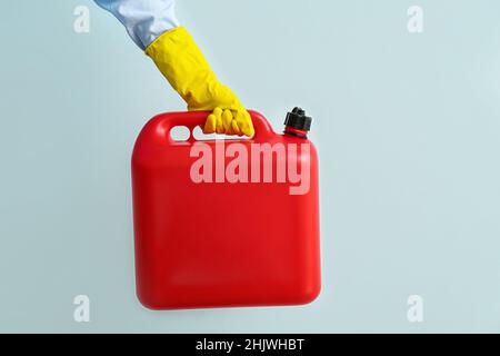 Main mâle dans des gants en caoutchouc tenant le réservoir sur fond de couleur Banque D'Images