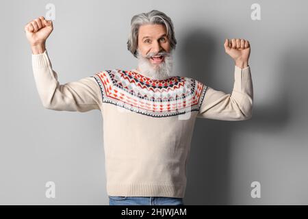 Beau homme heureux senior en pull tricoté sur fond gris Banque D'Images