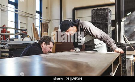 Portrait de deux ouvriers masculins retourné à l'appareil photo, regardant un bureau en bois.Tir horizontal.Vue avant Banque D'Images