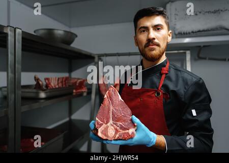 Une jeune boucherie tenant des steaks de viande crue dans le réfrigérateur de l'épicerie Banque D'Images