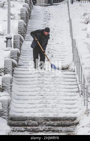 L'homme pelle la neige sur un escalier après une grosse tempête de neige, verticale Banque D'Images