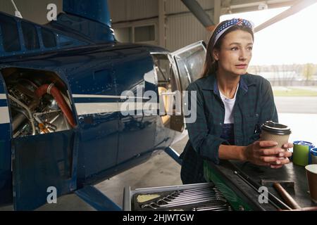 Femme mécanicien de moteur debout devant l'avion à réaction privé dans le garage Banque D'Images