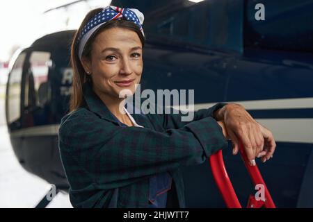Charmante femme élégante ingénieur moteur debout dans un garage aviationg Banque D'Images