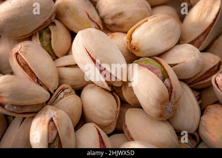 Fruits à coque non décortiqués et aliments végétariens sains gros plan sur une pile de pistaches grillées et salées en carapace (texture, fond) Banque D'Images