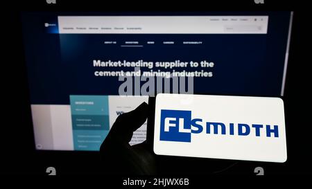 Personne tenant un smartphone avec le logo de l'ingénierie danoise FLSmidth Co. COMME sur l'écran devant le site Web.Mise au point sur l'affichage du téléphone. Banque D'Images