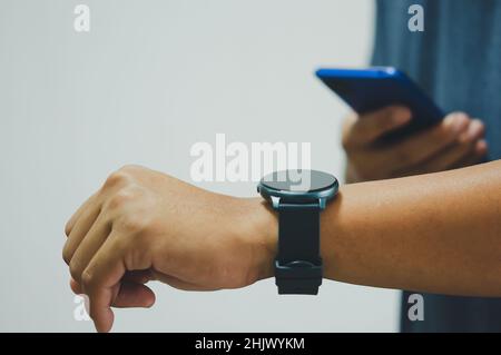 Gros plan Homme avec un téléphone mobile connecté à une montre intelligente. Banque D'Images